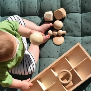 Baby with a mixture of wooden loose parts and wooden discovery box